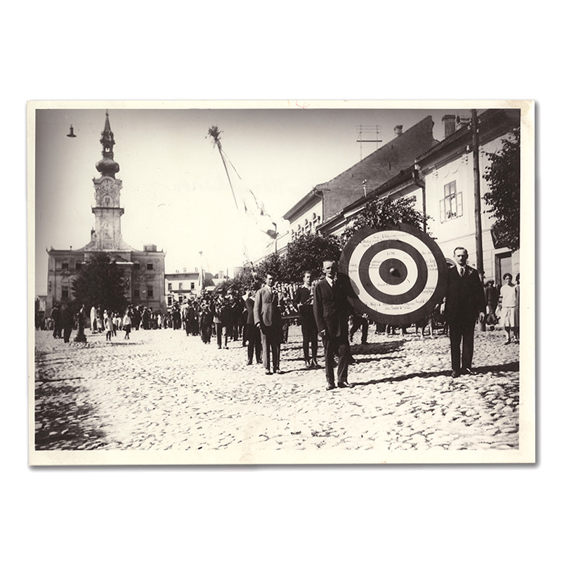 Fotografia pochodujúcich členov streleckého spolku na námestí v Kežmarku pri ceste na tzv. kráľovskú streľbu.